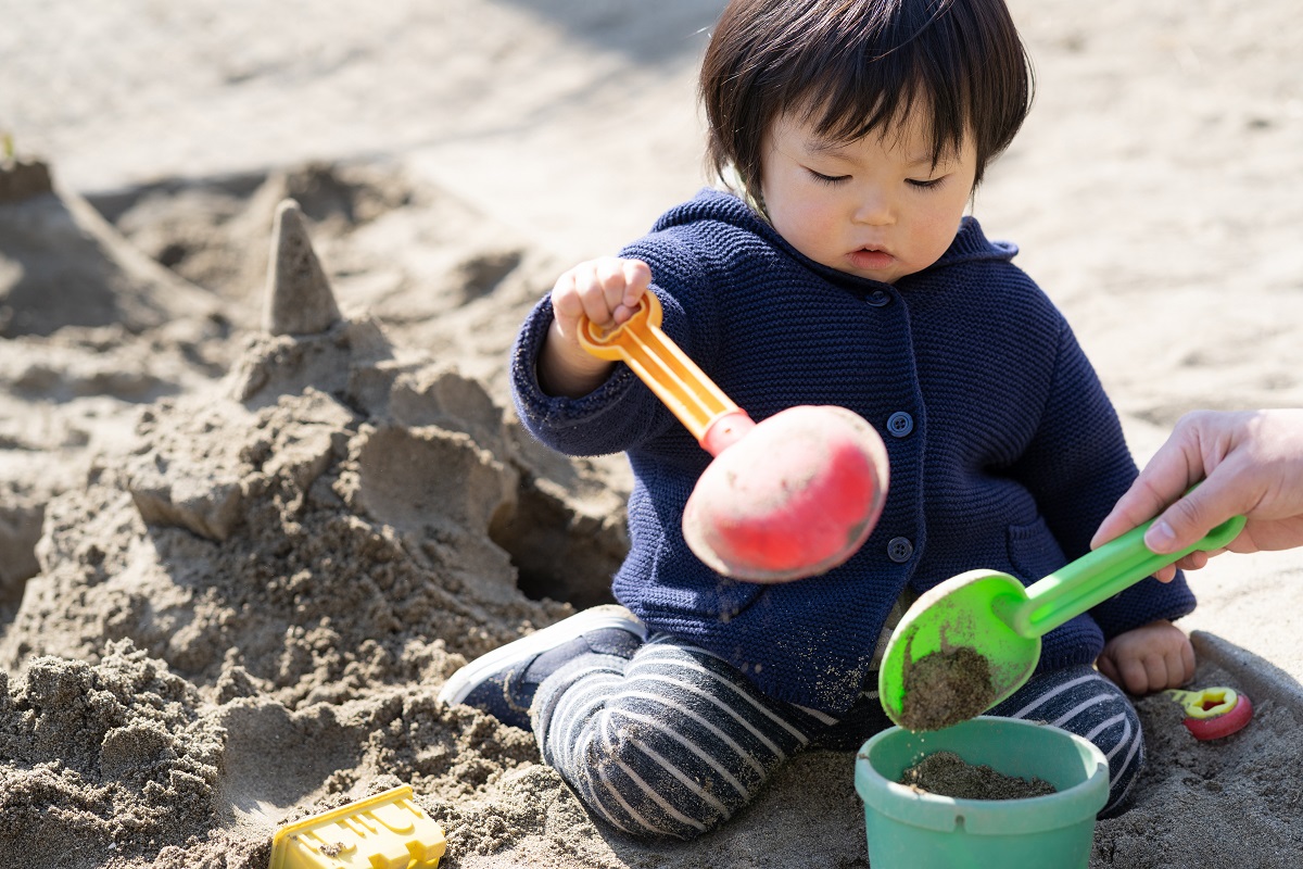 シャベルを使って砂場遊びをしている子供の写真