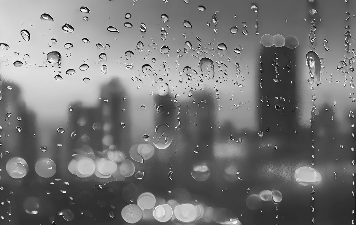 雨のついたガラス窓から見える都会のシルエット