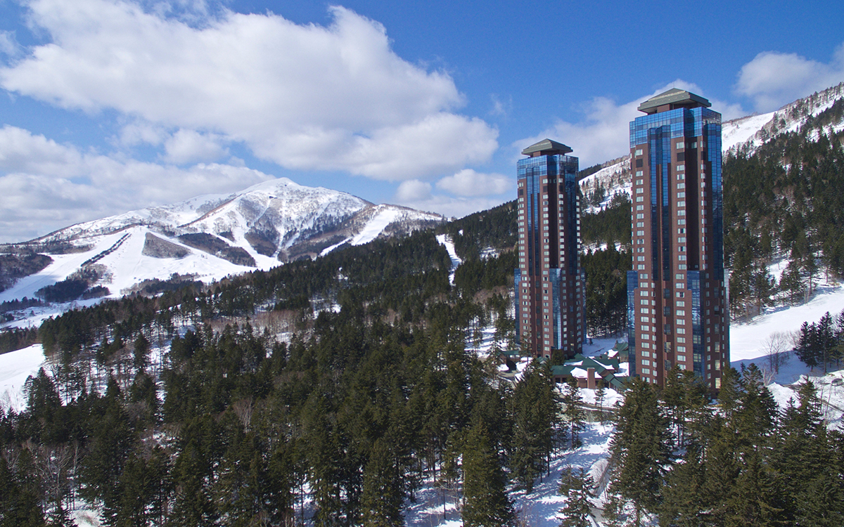 雪景色の高台に建つ2棟の高い建物の写真