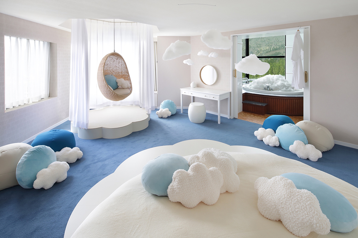 青色の絨毯が敷かれ、雲の形のクッションや装飾が散りばめられた部屋の写真