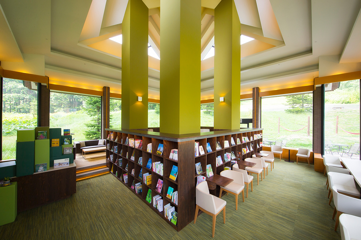 緑色の絨毯や柱があり、茶色い本棚が並んだ部屋の写真
