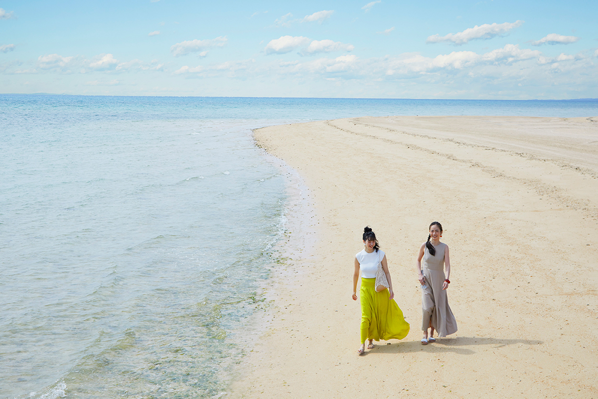海辺の砂浜を歩く二人組の写真