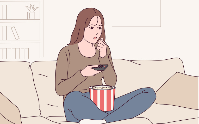 家でポップコーンを片手に映画を観る女性