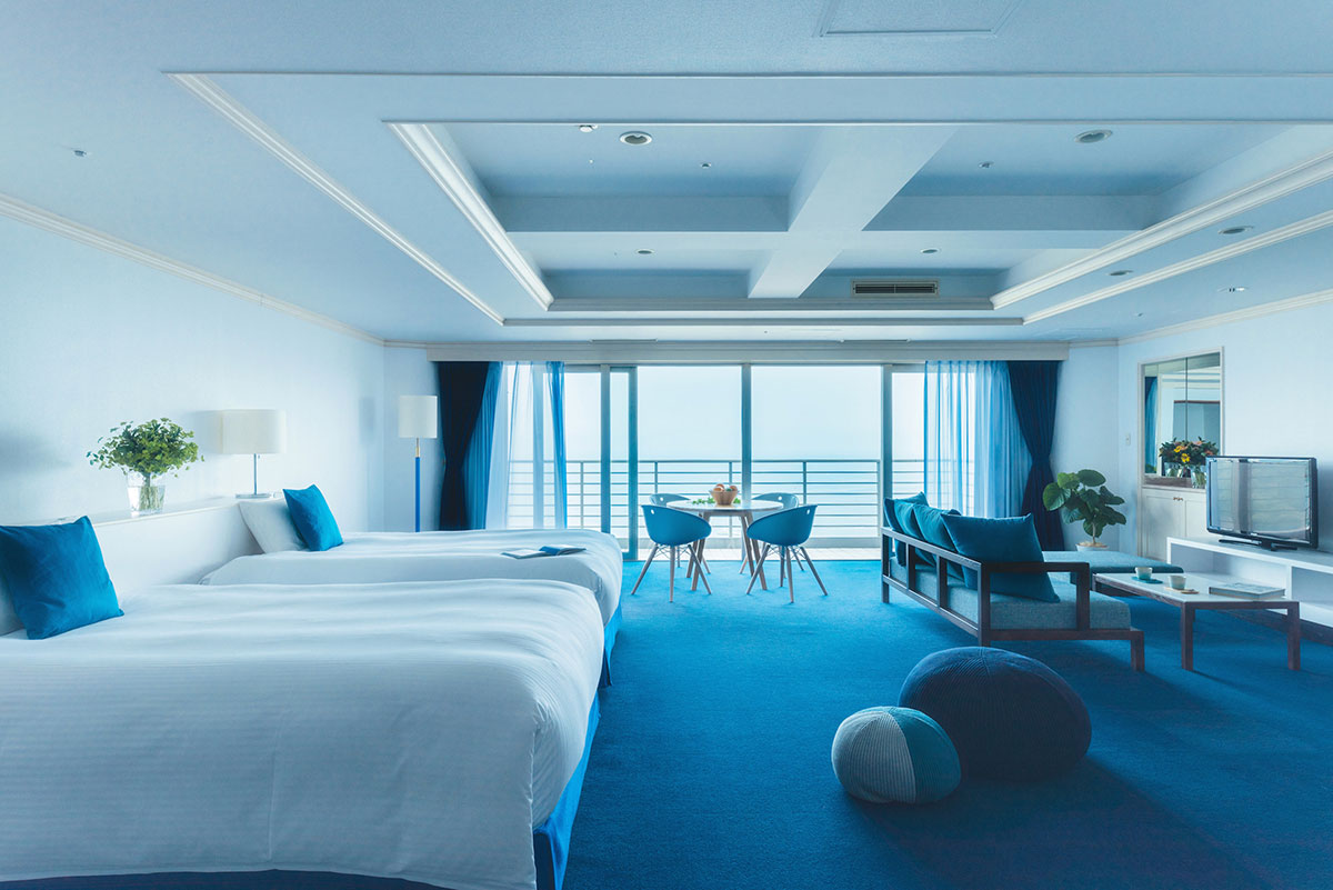 青い絨毯にベッドやソファが置かれた客室の写真