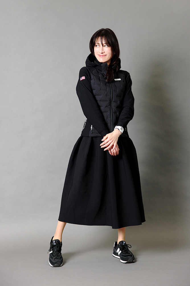 ドマーニラボメンバー 飯島美穂さん　黒のダウンジャケットと黒のニットスカートのコーデ　全身写真