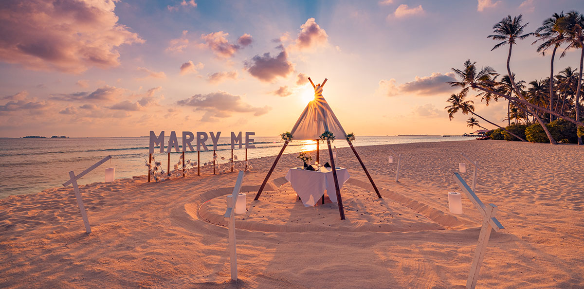 夕暮れのビーチに建てられた「MARRY ME」の看板