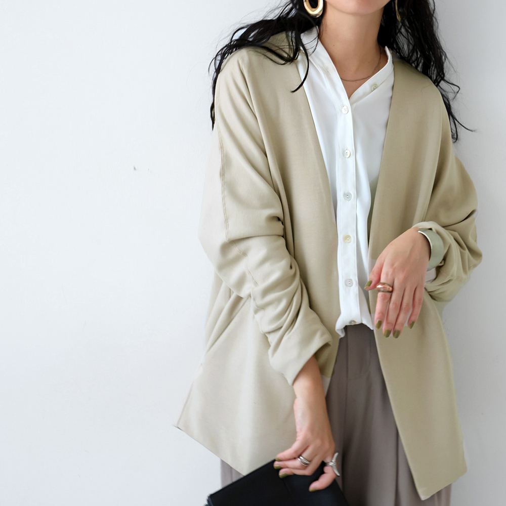 ベージュのジャケット・白のブラウス・グレージュのパンツを着用したモデルの写真