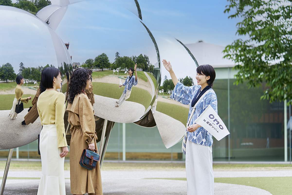 金沢21世紀美術館お散歩ツアー　作品の前で解説する人、話を聞いている2人の写真