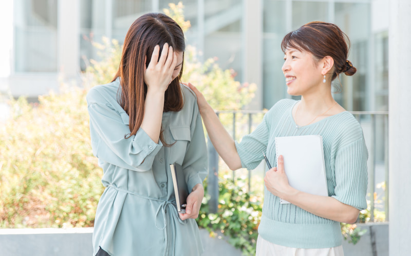 女性二人の写真。仕事に失敗した後輩を先輩が慰めている