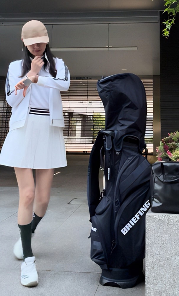 黒いキャディバッグとゴルフウエアを着た女性