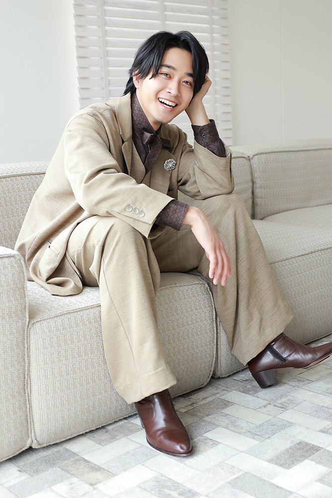 ソファに座って笑顔を見せる佐藤寛太さん