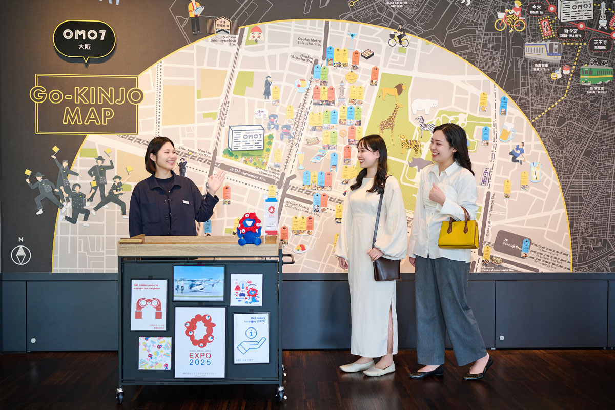 OMO7大阪　ご近所マップの前で会話している人々