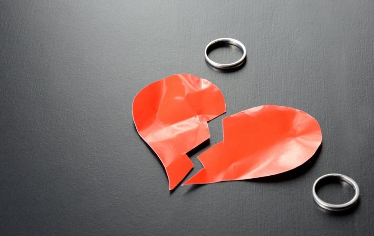 割れたハートと指輪が二つ置かれている写真
