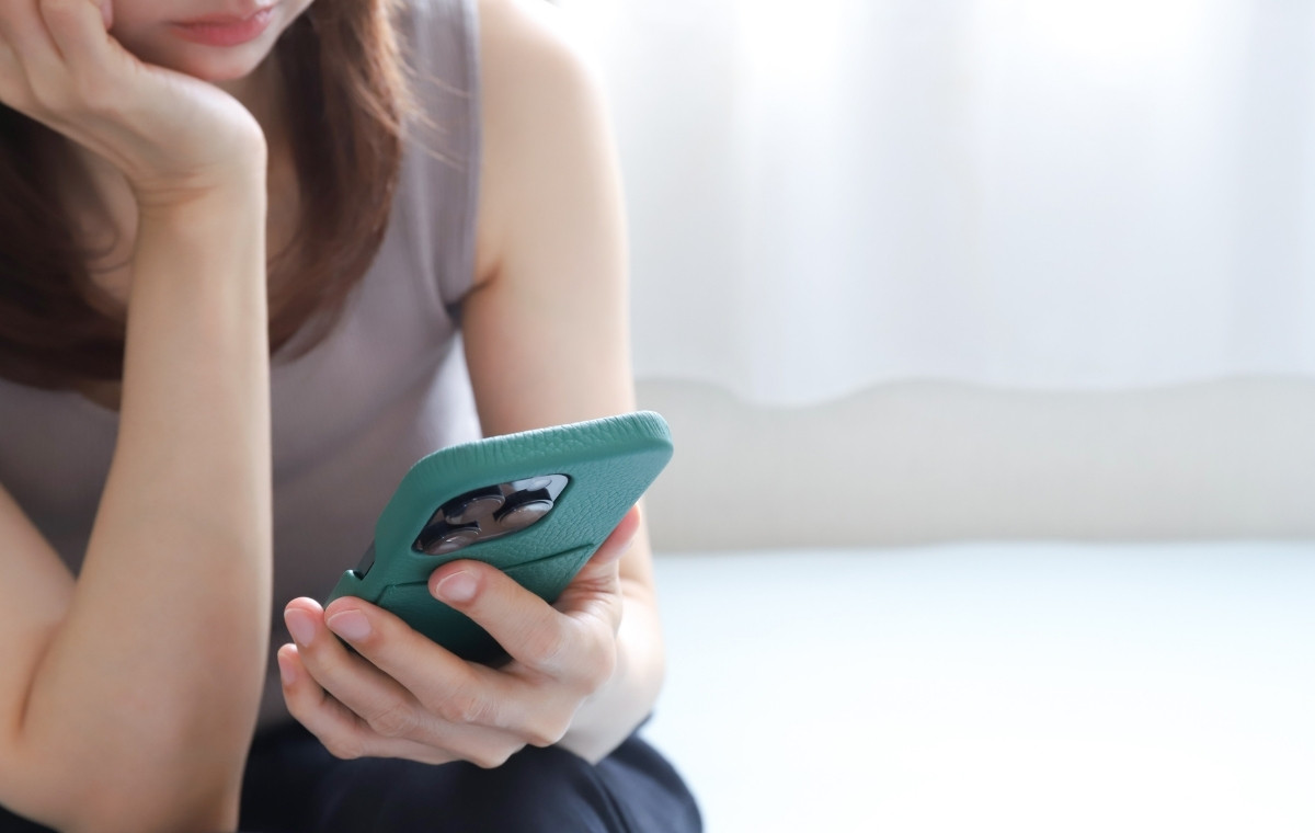 スマホを見ながら憂鬱そうな女性の写真