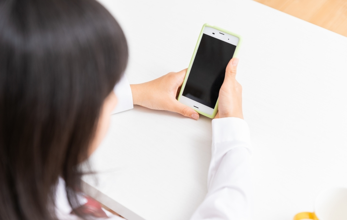 スマホを見る女子学生の写真