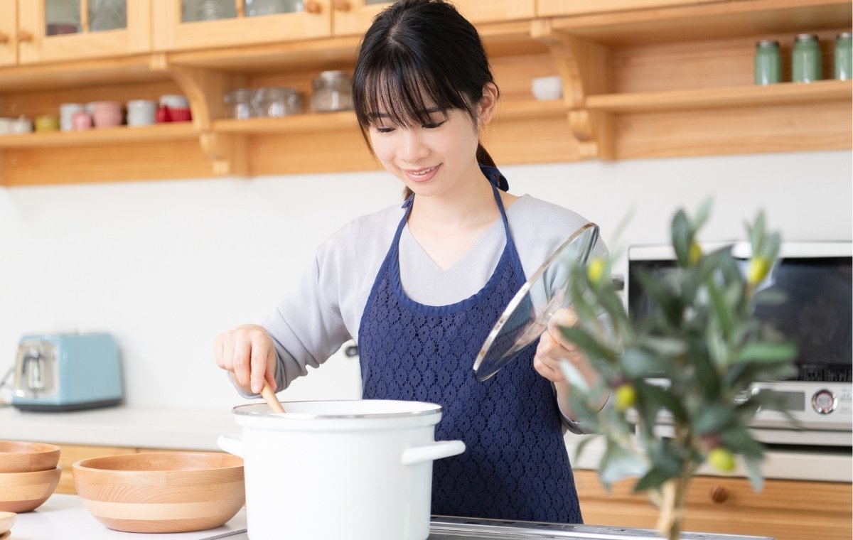 鍋を覗く調理中の女性の写真