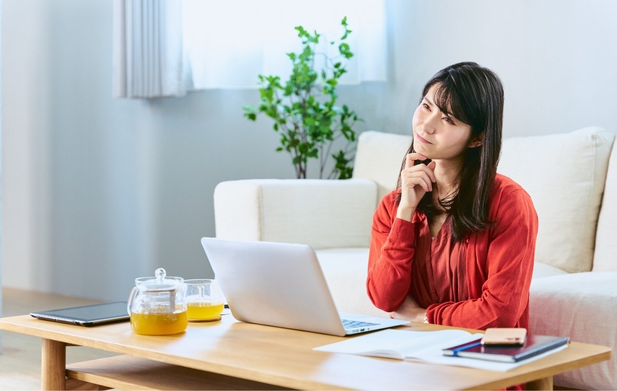 リモートワーク中にPCの前で考える女性の写真