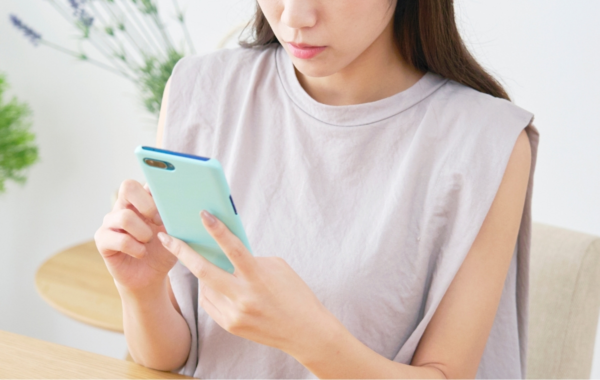 スマホを見て心配そうな顔をしている女性の写真