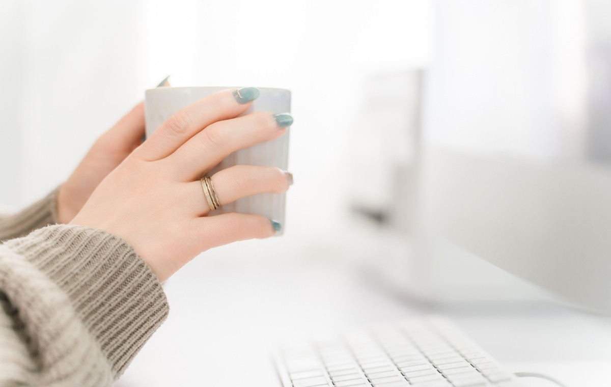 パソコンの前で一息つく女性の手元の写真