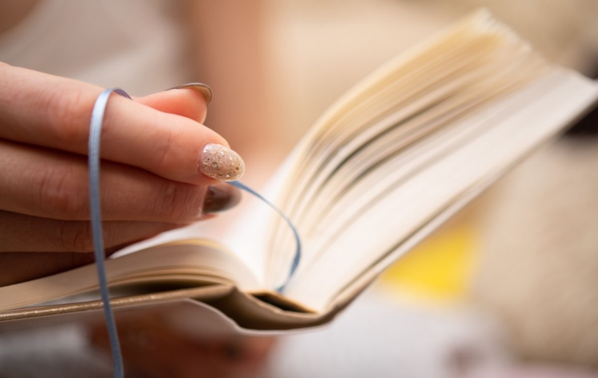本にしおりを挟もうとしている女性の手元の写真
