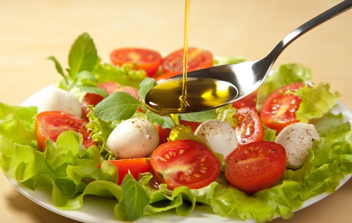サラダにオリーブオイルをかけている写真