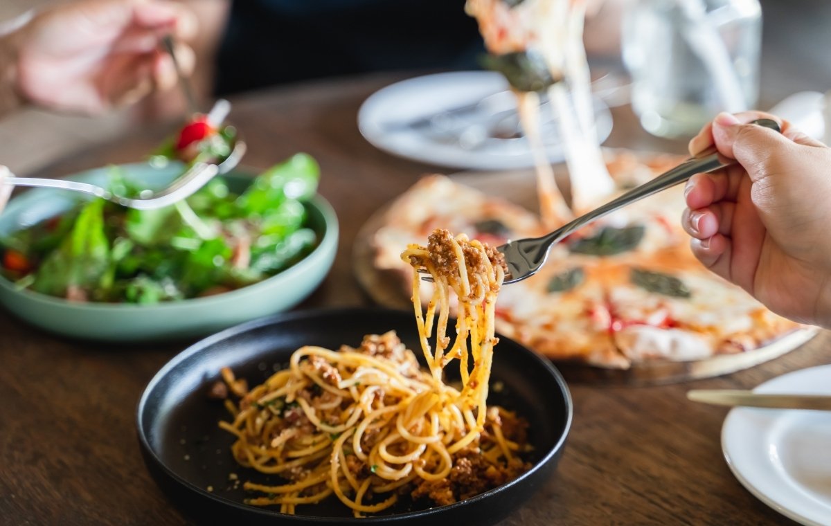 パスタ・ピザ・サラダを食べる人々の写真