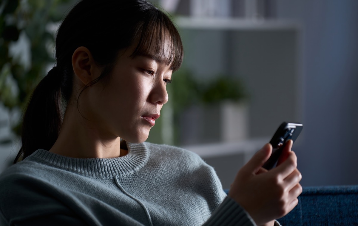 携帯みながら落ち込む女性