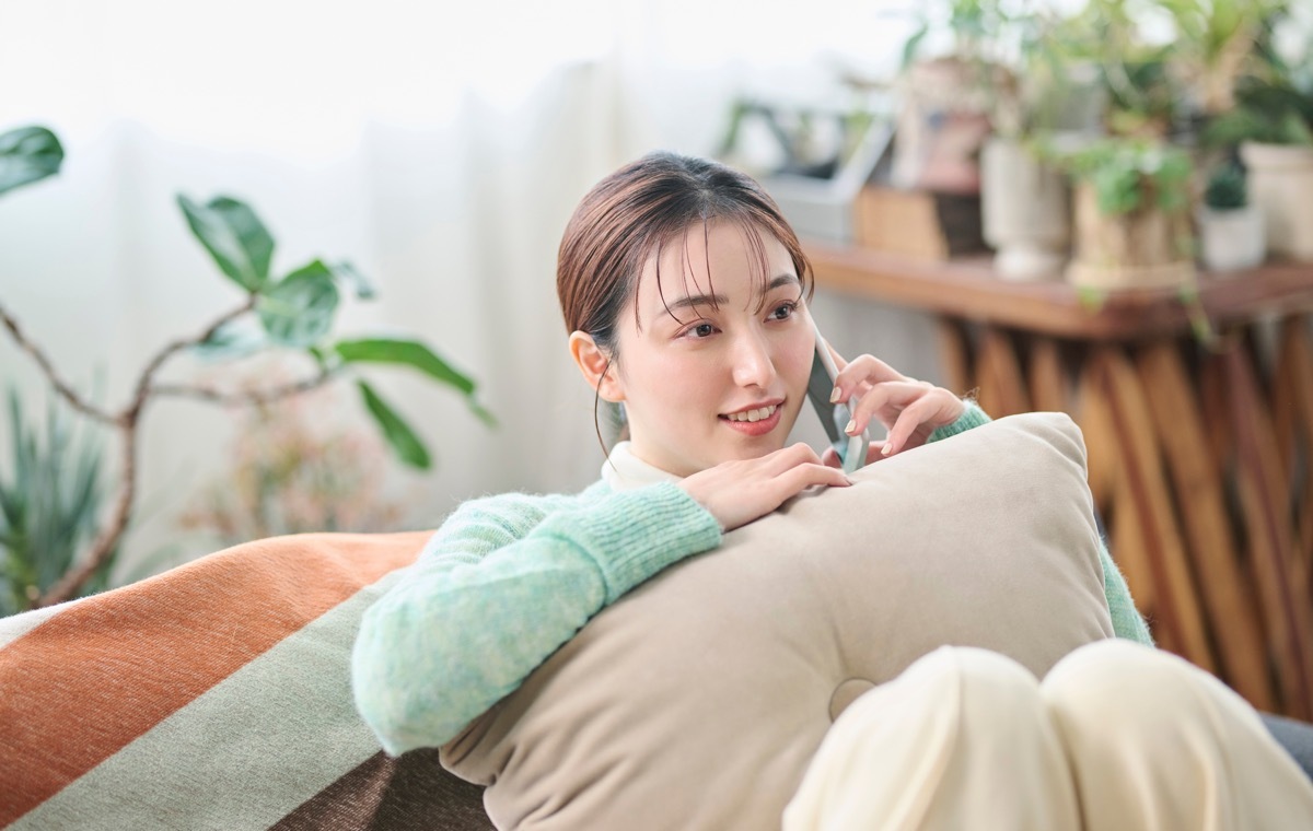 枕を抱えて通話する女性