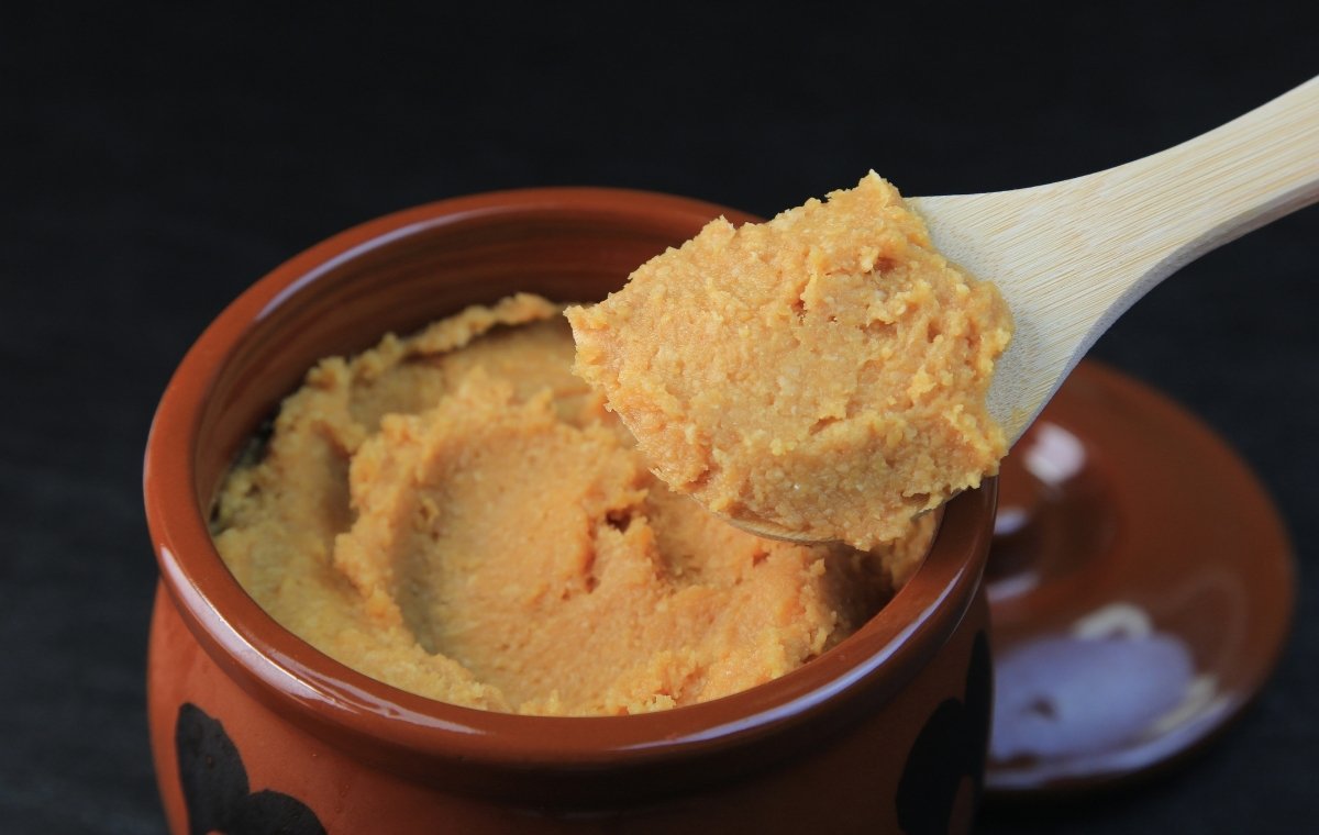 ツボに入った味噌を木のおさじですくっている写真