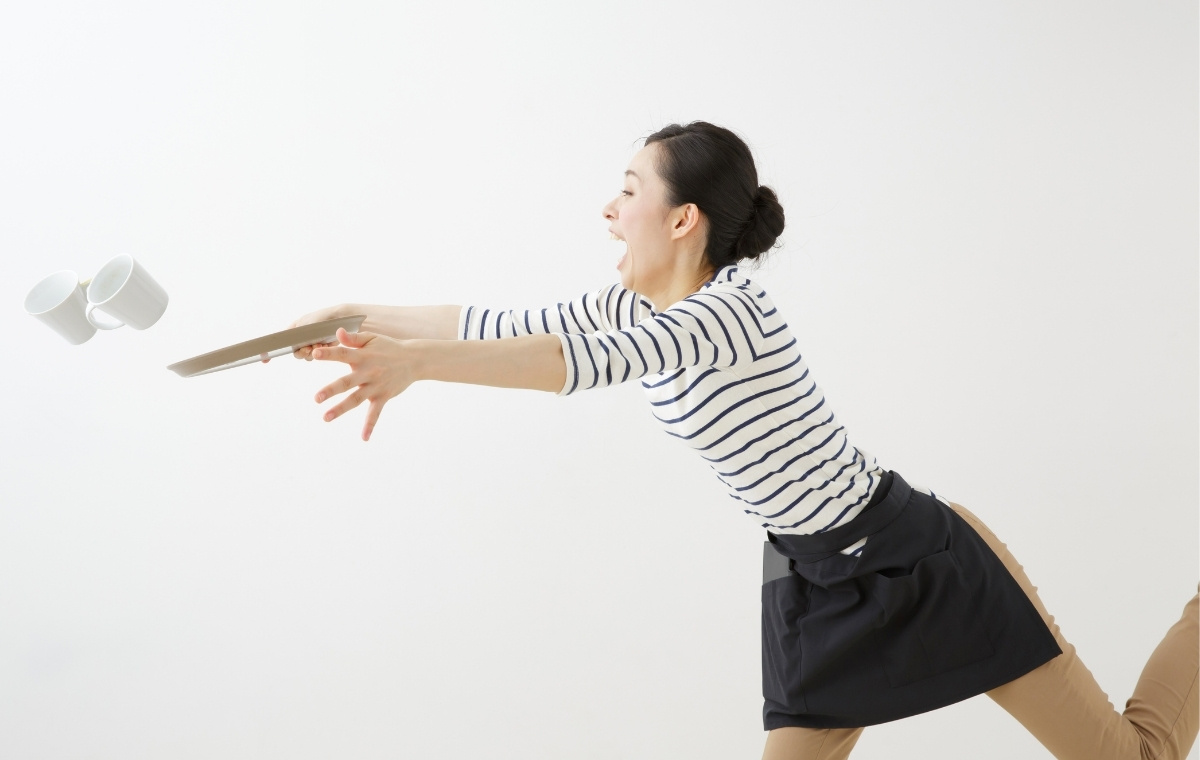 つまずいてコーヒーを飛ばす女性店員の写真