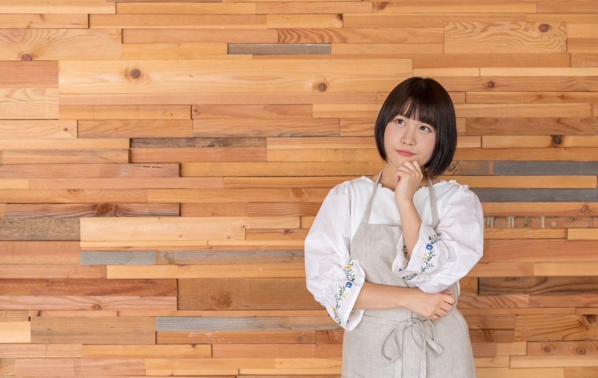 エプロン姿で考える女性の写真