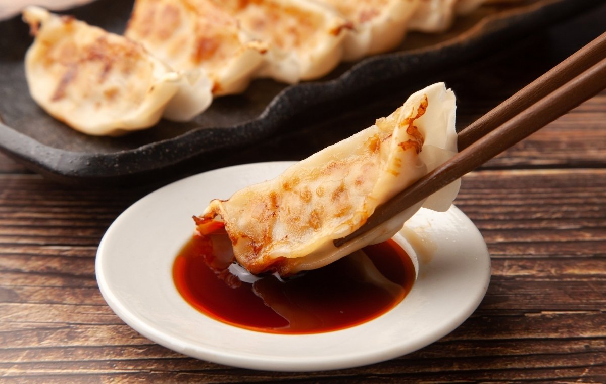 ラー油入りのたれに餃子をつけている写真