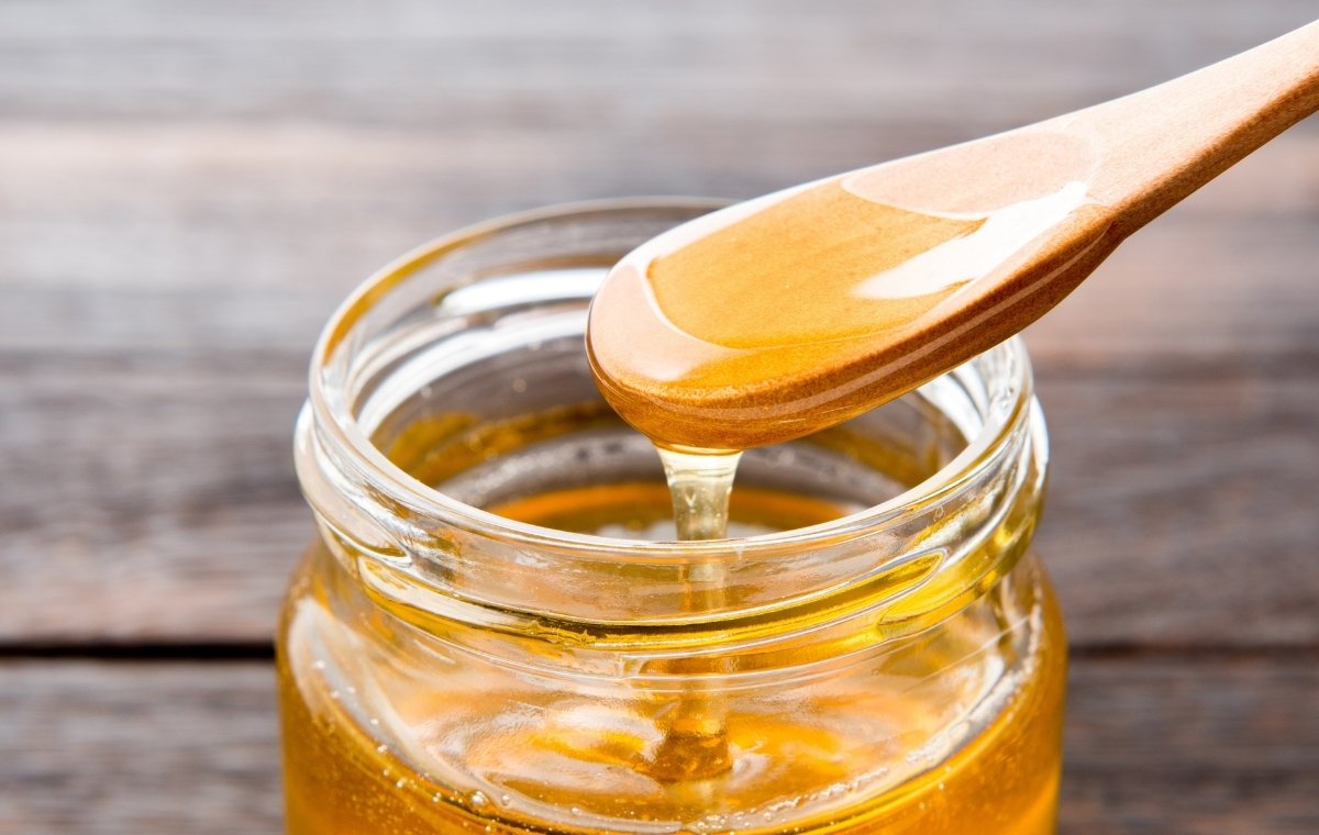 瓶に入ったハチミツをスプーンですくっている写真