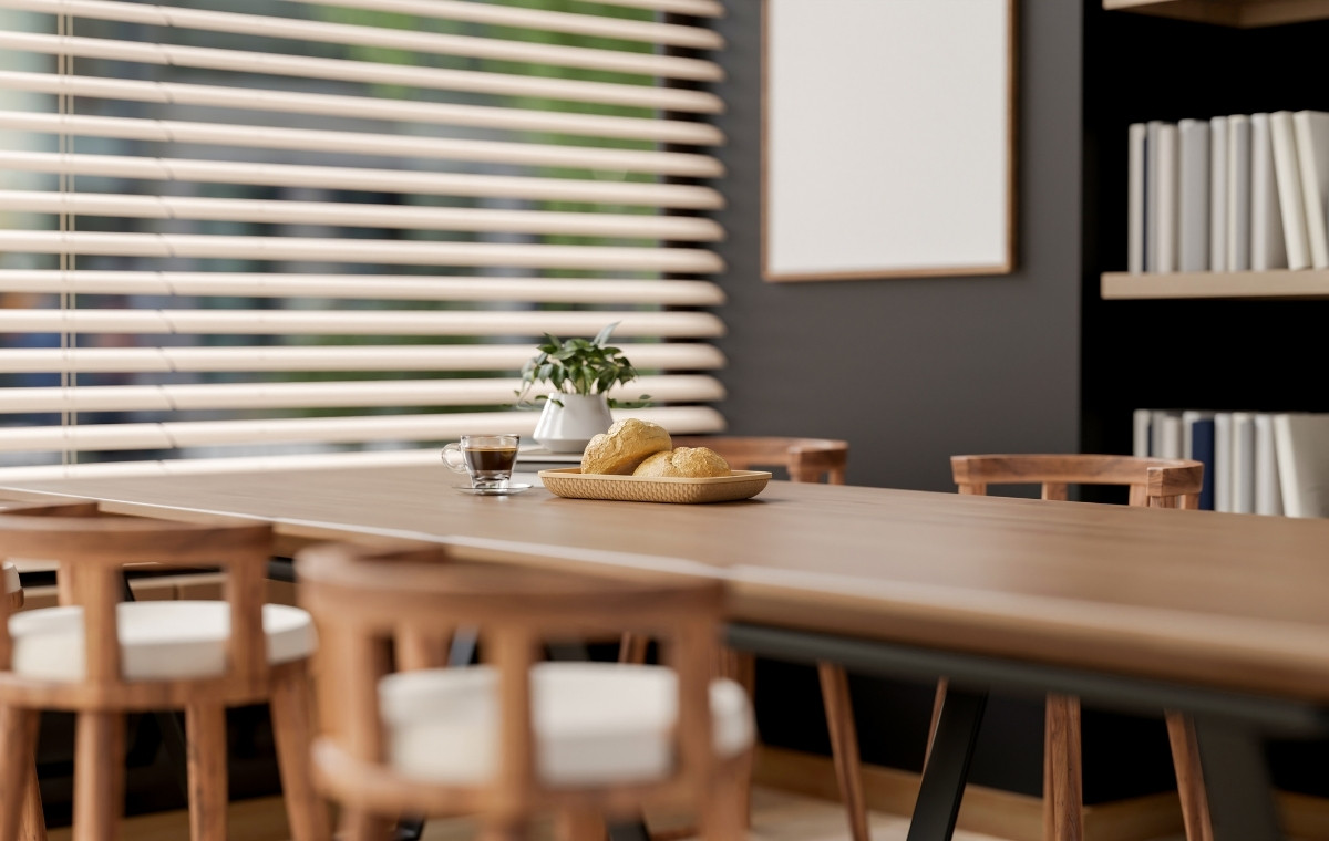 ブラインドのある部屋のテーブルにパンとコーヒーが置かれている写真