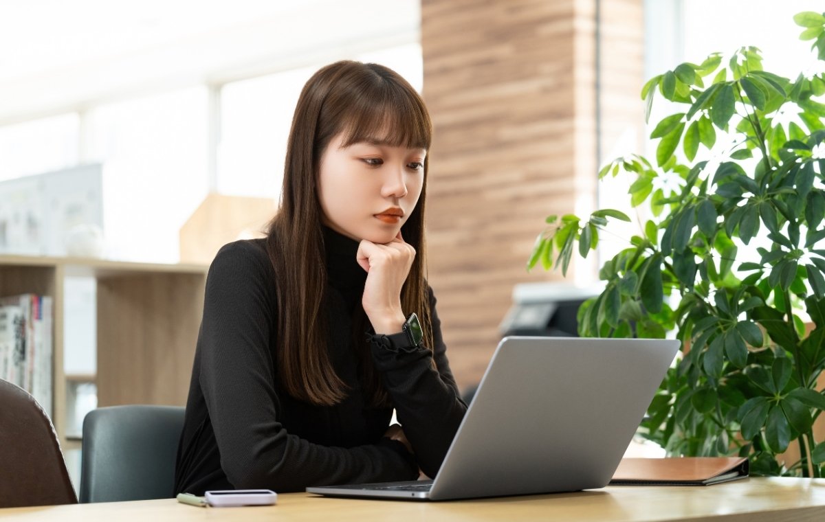 ノートパソコンの前で考えている女性の写真