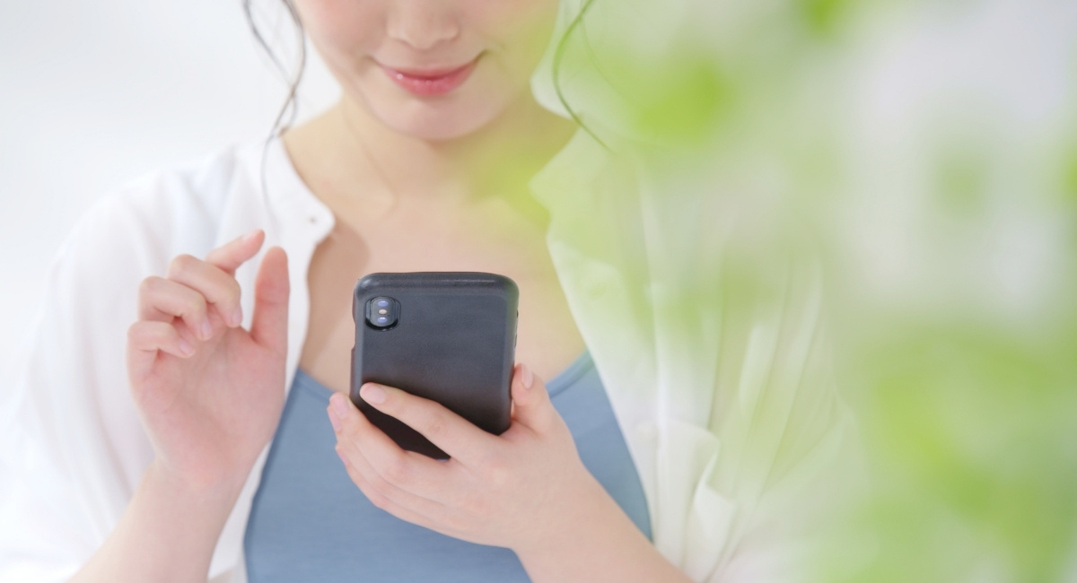 スマホを操作しながら微笑む女性の写真