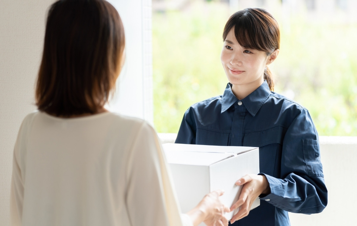 配達員の女性から荷物を受け取る女性の写真