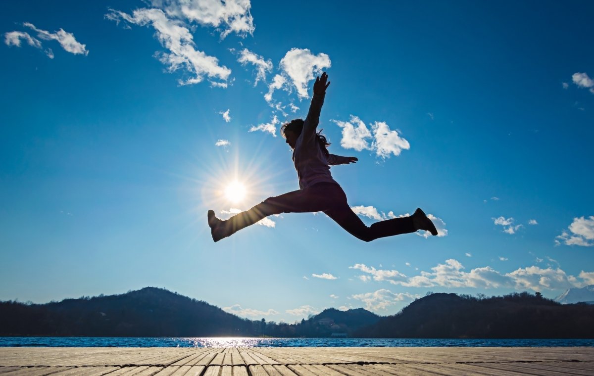 広々とした青空の下でジャンプする女性の写真