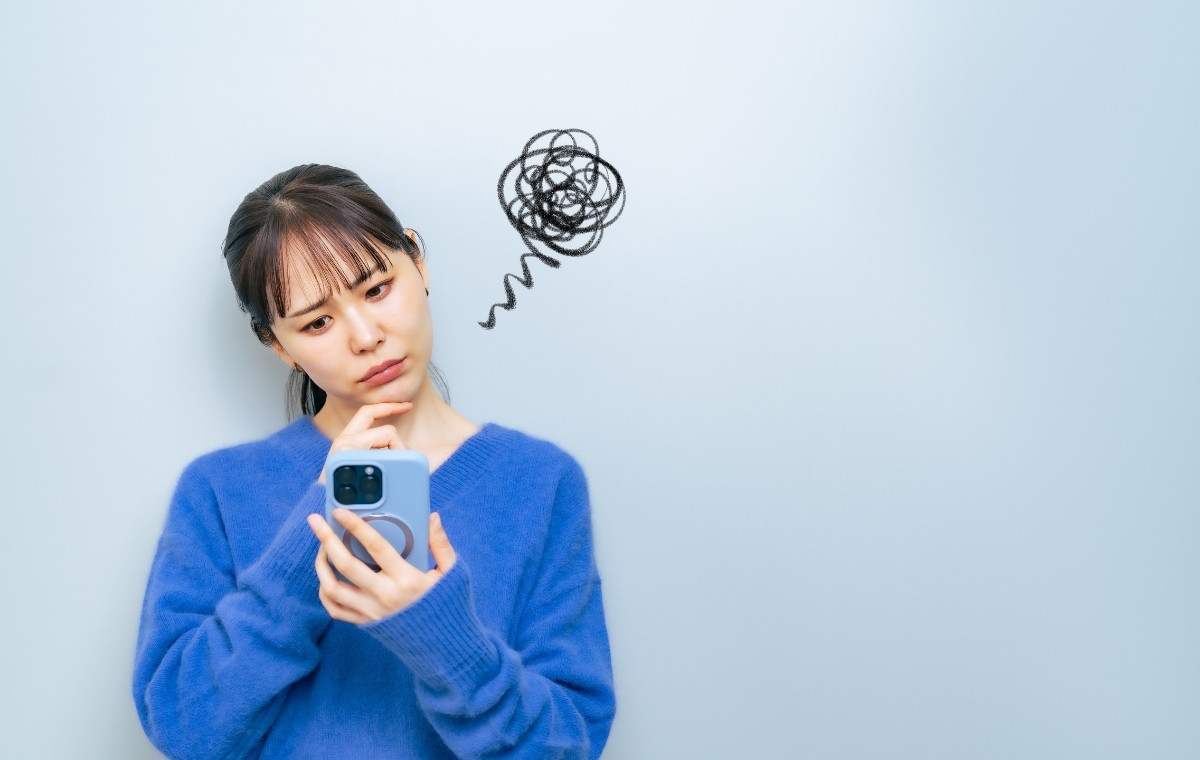 スマホ操作中に不機嫌な表情をしている女性の写真