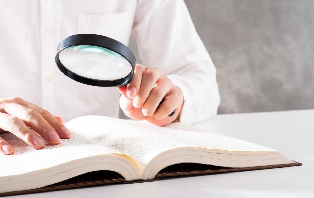 辞書をルーペで見る人の写真