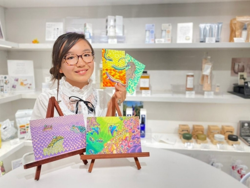 ぬりえを手に持ってほほ笑むConocaさんの写真