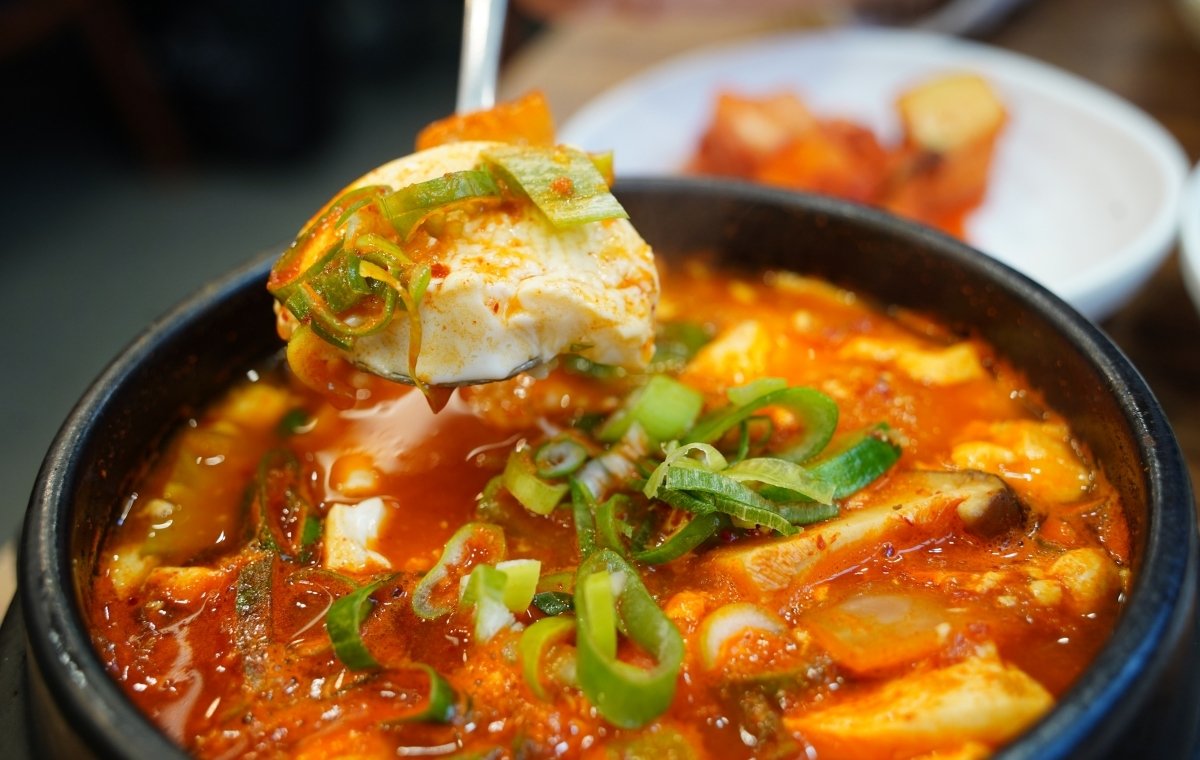 石鍋のスンドゥブをスプーンですくっている写真