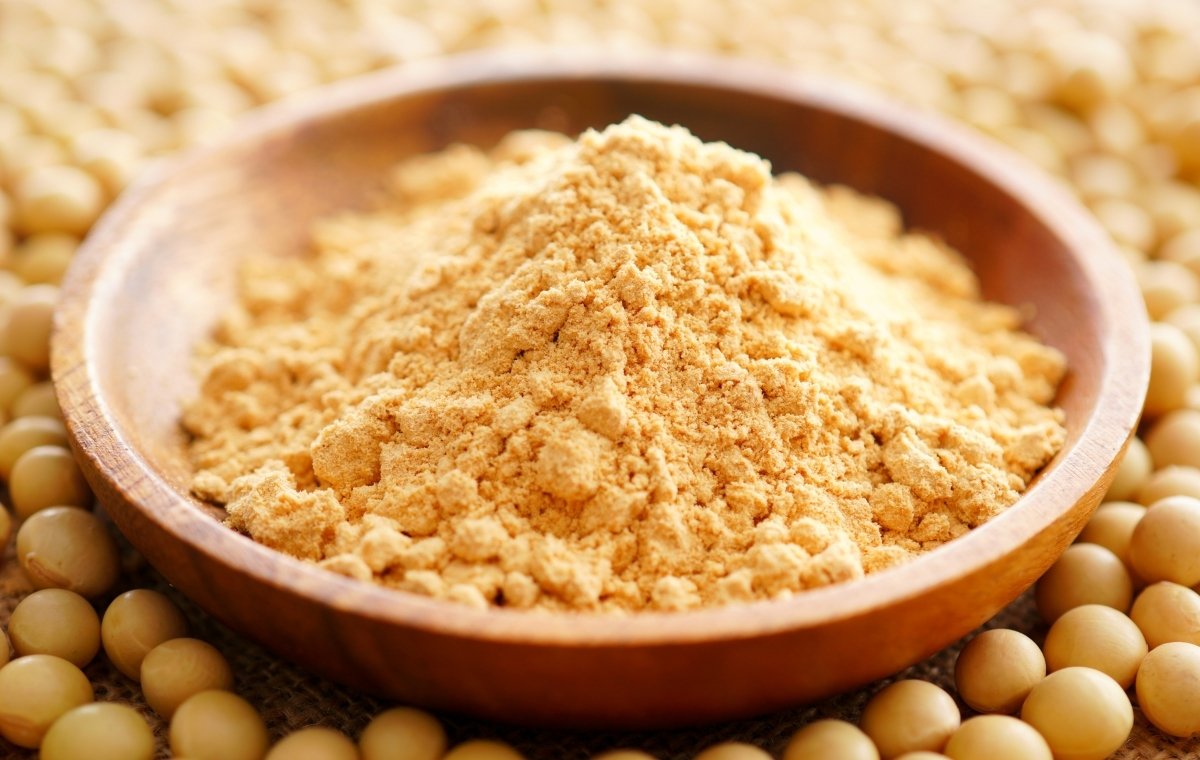 大豆の上に、きな粉が盛られた木の器が置かれている写真