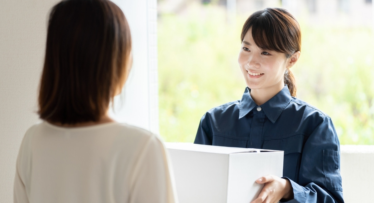 女性配達員から荷物を受け取る写真