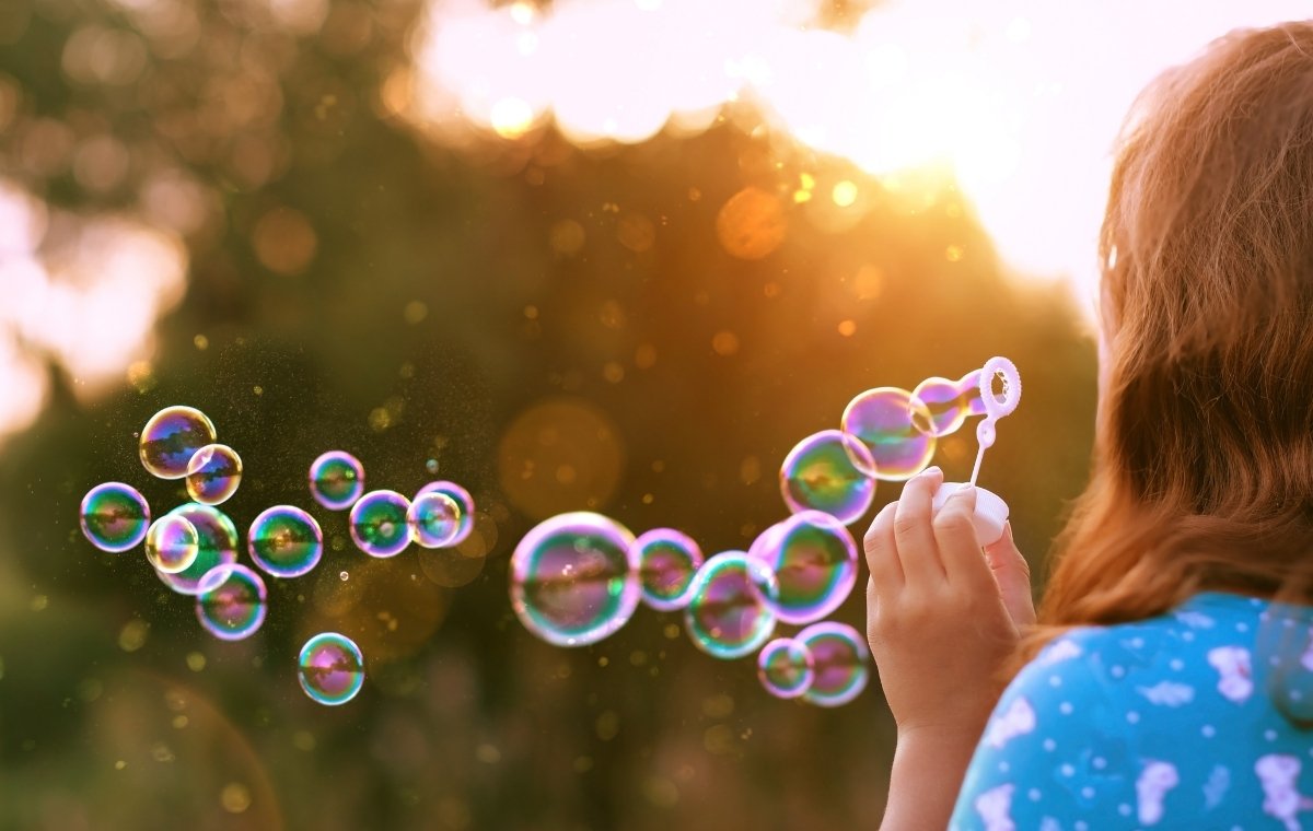 夕暮れにシャボン玉を吹いている女性の写真