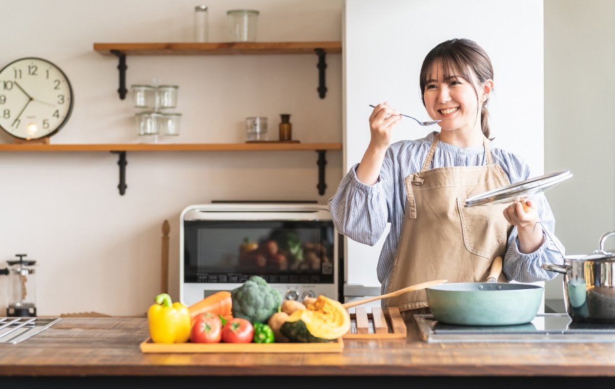 キッチンで味見している調理中の女性の写真