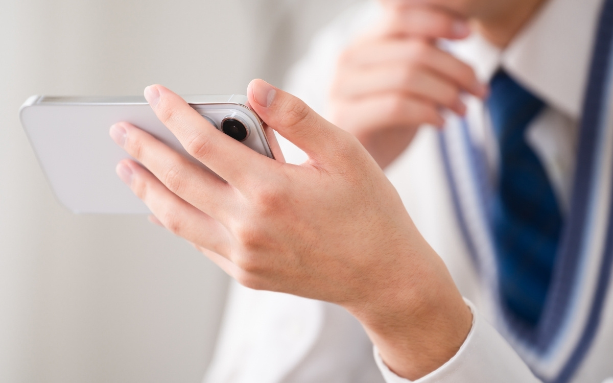 スマホを見ている男子学生の写真