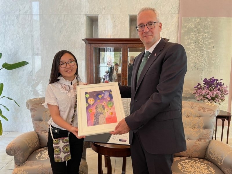 トルコ大使館の方と作品を手に持ってほほ笑むConocaさんの写真