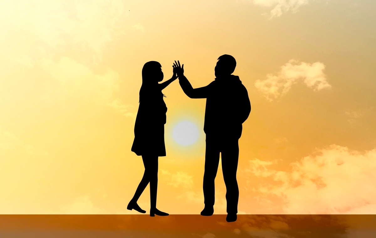 夕日に手を取り合う男女