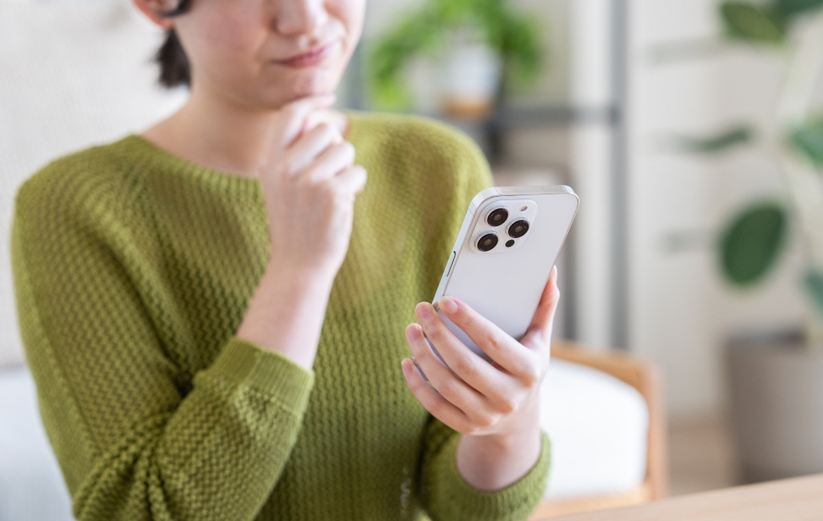 スマホを見て考え込む女性の写真